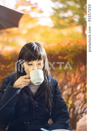 一位女士在露台上的咖啡館喝茶,露台上有美麗的秋葉 一位女士在露台上的咖啡館喝茶,露台上有美麗的秋葉 95857850
