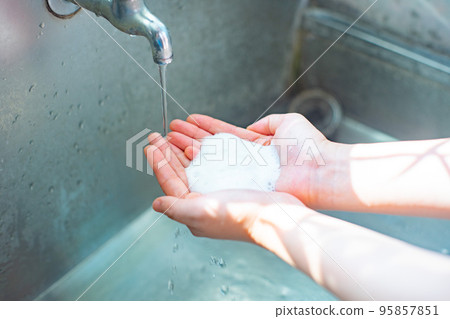 在水龍頭下用泡沫洗手液洗手的人的手 95857851