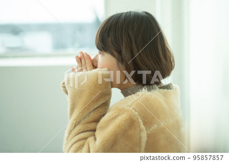 一名身穿大衣的女士在巴士候車室暖手 一名身穿大衣的女士在巴士候車室暖手 95857857