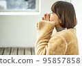一名身穿大衣的女士在巴士候車室暖手 95857858