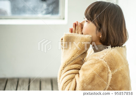 一名身穿大衣的女士在巴士候車室暖手 一名身穿大衣的女士在巴士候車室暖手 95857858