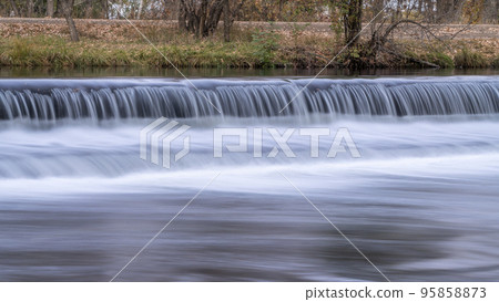 Water cascading over a river diversion dam 95858873