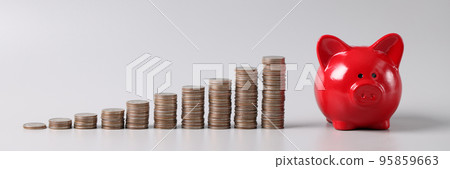 Stack of coins in ascending order and red piggy bank on table, profitable investment of funds Stack of coins in ascending order and red piggy bank on table, profitable investment of funds 95859663