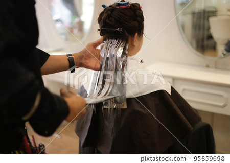 Male hairdresser coloring woman's hair 95859698
