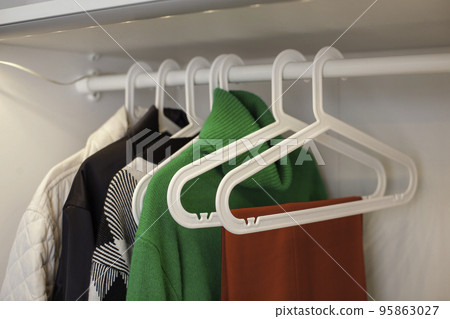 Clothes hang on a hanger in the closet. 95863027