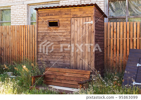 Wooden outdoor toilet in the yard closeup 95863099