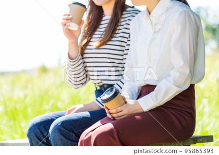 兩名年輕的女大學生在公園裡喝咖啡 兩名年輕的女大學生在公園裡喝咖啡 95865393