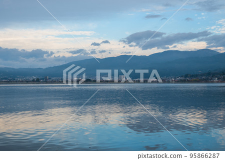 Blue sky, clouds and mountains reflected on the surface of the lake in the morning 95866287