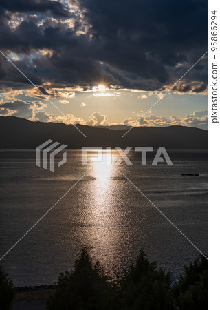 The setting sun reflecting the light on the surface of the lake 95866294