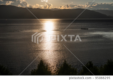 The light of the setting sun shining on the surface of the lake 95866295