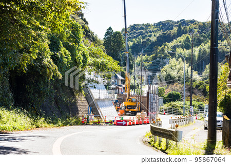 One-way traffic during road construction with a rough terrain crane vehicle One-way traffic during road construction with a rough terrain crane vehicle 95867064