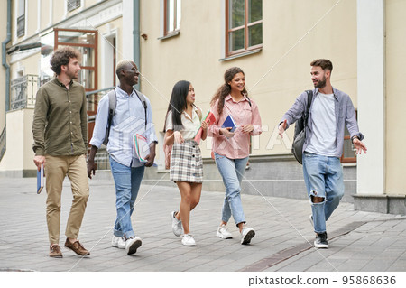 multiethnic group of students walking down a city street . multiethnic group of students walking down a city street . 95868636