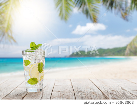 Mojito cocktail on wooden table in front of sunny sea Mojito cocktail on wooden table in front of sunny sea 95868808