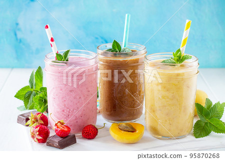 Strawberry, chocolate and apricot smoothie on a white wooden background. Healthy juicy vitamin drink diet or vegan food concept. 95870268