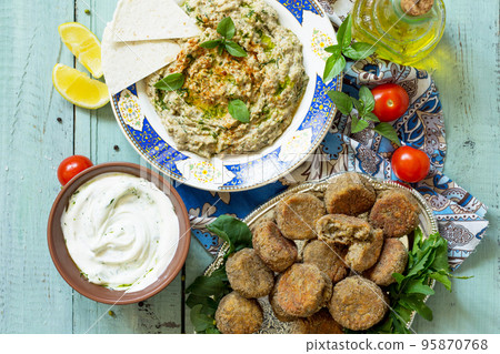 Arabic cuisine. Fresh homemade creamy mung hummus with spicy, falafel, sour cream sauce. Ramadan food. Top view flat lay background. Arabic cuisine. Fresh homemade creamy mung hummus with spicy, falafel, sour cream sauce. Ramadan food. Top view flat lay background. 95870768
