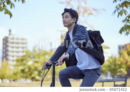Young Japanese man in a jacket riding a bicycle Young Japanese man in a jacket riding a bicycle 95871452