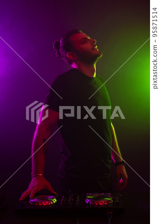 DJ playing music at mixer on colorful foggy background 95871514