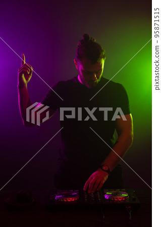 DJ playing music at mixer on colorful foggy background 95871515