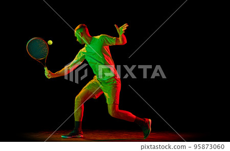 Young sportive man, professional tennis player in motion, action isolated over dark background in neon light. Concept of professional sport, competition, skills. Young sportive man, professional tennis player in motion, action isolated over dark background in neon light. Concept of professional sport, competition, skills. 95873060