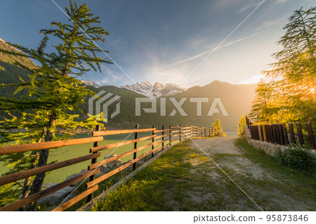 Alpine lake and mountain road at springtime, Gran Paradiso Alps, Italy Alpine lake and mountain road at springtime, Gran Paradiso Alps, Italy 95873846