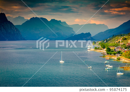 Above idyllic Lake Garda with sailboats in Malcesine at sunset, Italian alps 95874175