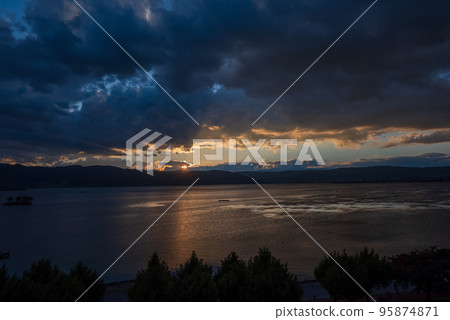 The setting sun while leaving the light on the surface of the lake 95874871