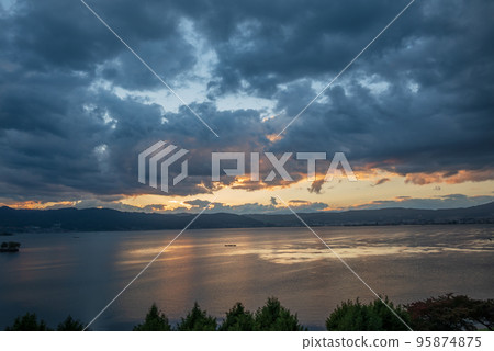 The setting sun illuminating the lake surface and clouds The setting sun illuminating the lake surface and clouds 95874875