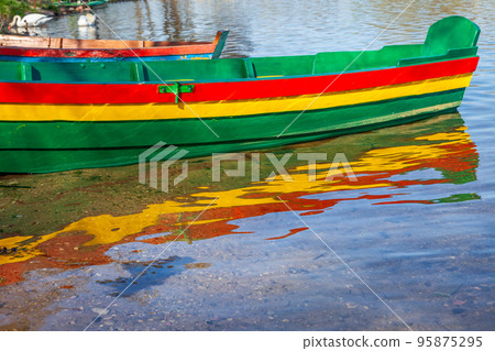 Boats with lithuanian flag colors at lake shore in morning, Lithuania 95875295