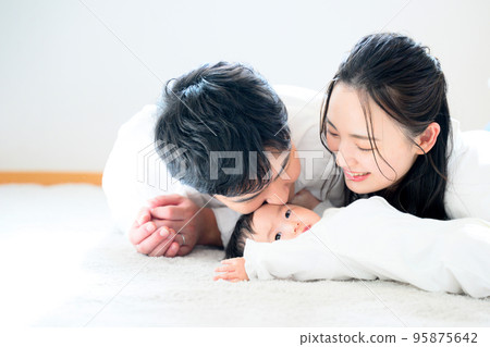 A portrait of a young couple and a baby lying down in the living room 95875642