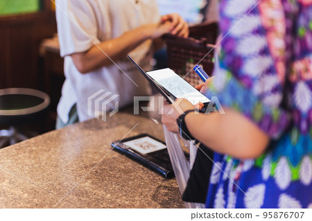 Woman customer scanning QR code payment via mobile phone at cashier counter in store. 95876707