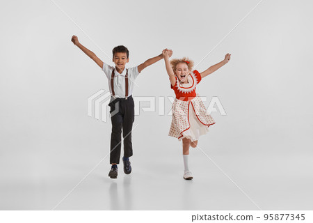 Portrait of beautiful little children, boy and girl in vintage clothes isolated over grey background. Back to school 95877345