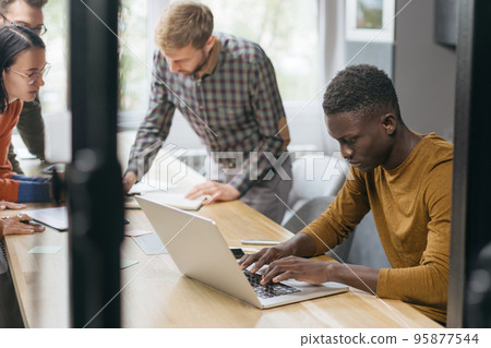 young businessman sitting at a table in a coworking center. 95877544