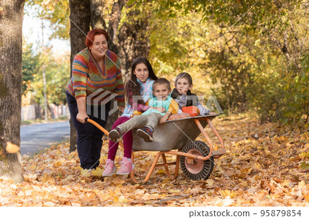 Mother have fun time with kids, use garden wheelbarrow with pumpkins Mother have fun time with kids, use garden wheelbarrow with pumpkins 95879854