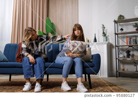 Mother daughter conflict. Middle aged woman trying to speak to her offended adult daughter, sitting together on sofa at home 95880127
