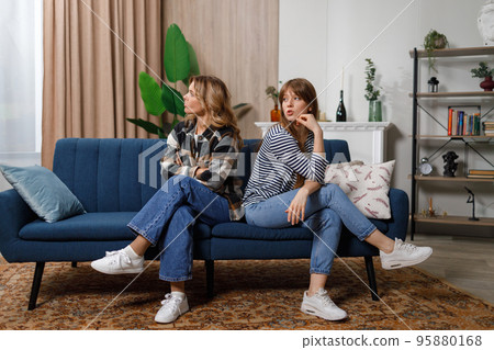 Family conflict. Offended mature woman and her adult daughter are sitting on the sofa with their backs to each other 95880168