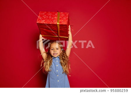 Great gift. Happy smiling little girl, child in casual outfit with box in festive package at holiday. Merry Christmas, New Year. Concept of emotions, dreams, birthday, happy childhood, wishes Great gift. Happy smiling little girl, child in casual outfit with box in festive package at holiday. Merry Christmas, New Year. Concept of emotions, dreams, birthday, happy childhood, wishes 95880259