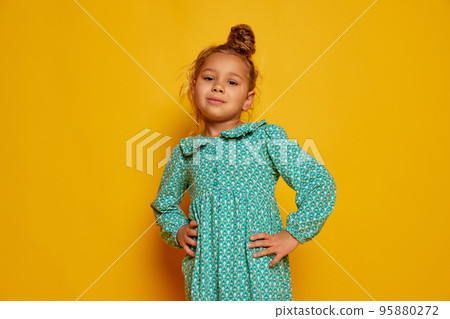 Smiling child. Cute little girl, kid with long curly hair looking at camera isolated over yellow background. Concept of children positive emotions, beauty 95880272