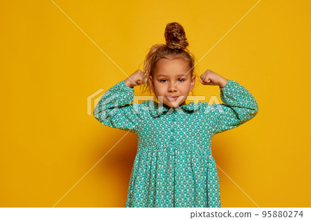 Cute little girl, kid with long curly hair looking at camera isolated over yellow background. Concept of children positive emotions, beauty Cute little girl, kid with long curly hair looking at camera isolated over yellow background. Concept of children positive emotions, beauty 95880274
