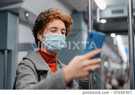 young woman talking on her smartphone in a subway car. 95880367