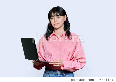 Teenage female student using laptop, looking at camera on light background 95881125