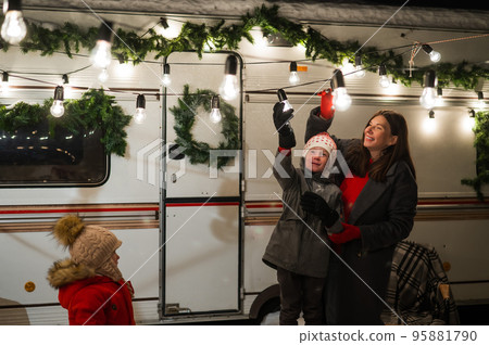 Caucasian woman and son decorate camper for christmas. Happy family travels in a mobile home. Caucasian woman and son decorate camper for christmas. Happy family travels in a mobile home. 95881790