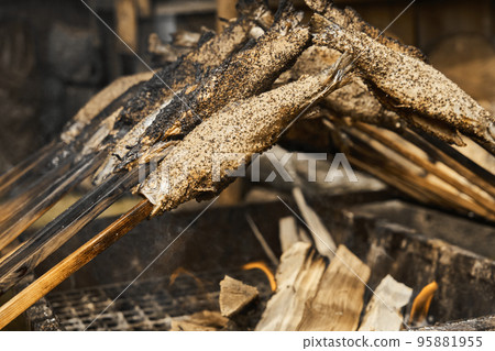 Trout skewered on a wooden stick grill over an open fire 95881955