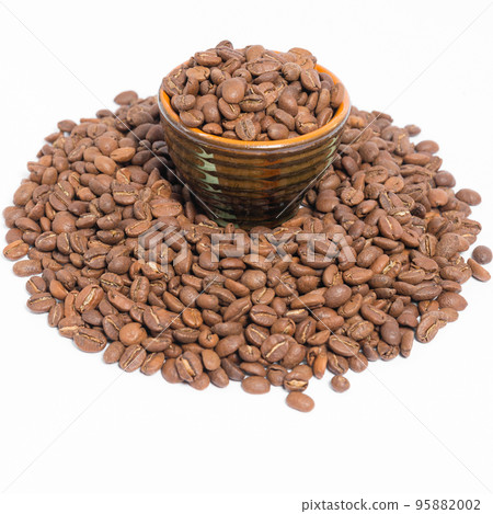 A small saucer with coffee beans stands on a pile of coffee on a white background. A small saucer with coffee beans stands on a pile of coffee on a white background. 95882002