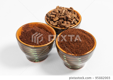 Cups with roasted coffee beans and ground coffee, white background and copy space. 95882003