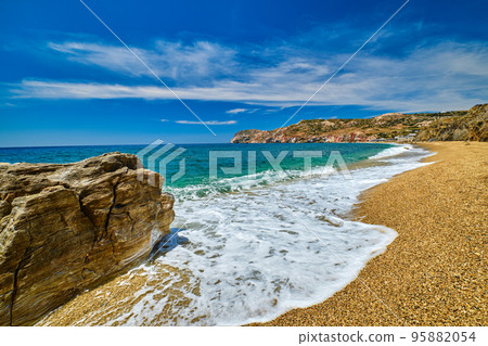 Sunny summer day on pebble and sandy beach, waves, spray, rocks.  95882054