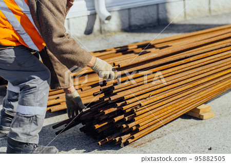 Slinger stacks thin metal pipes in stack on construction site. Close-up. Real workflow. Unloading of 95882505