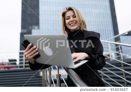 ambitious successful woman in a business suit with a laptop in her hands against the backdrop of a ambitious successful woman in a business suit with a laptop in her hands against the backdrop of a 95883687