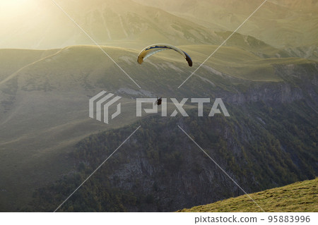 People planning on a parachute against the backdrop of beautiful mountains and sunset People planning on a parachute against the backdrop of beautiful mountains and sunset 95883996