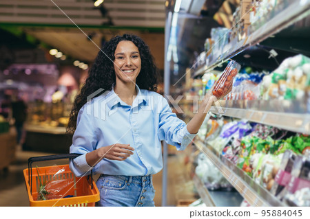 Portrait of beautiful vegetarian woman in supermarket, Latin American woman chooses vegetables for dinner, smiling and looking at camera. Portrait of beautiful vegetarian woman in supermarket, Latin American woman chooses vegetables for dinner, smiling and looking at camera. 95884045