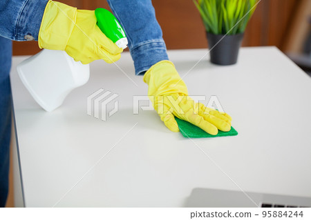 Beautiful young woman wearing protective gloves cleaning the desk in office Beautiful young woman wearing protective gloves cleaning the desk in office 95884244